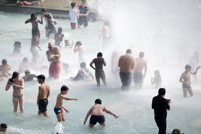 Người dân tránh nóng tại đài phun nước ở Paris, Pháp. Ảnh: THX/TTXVN