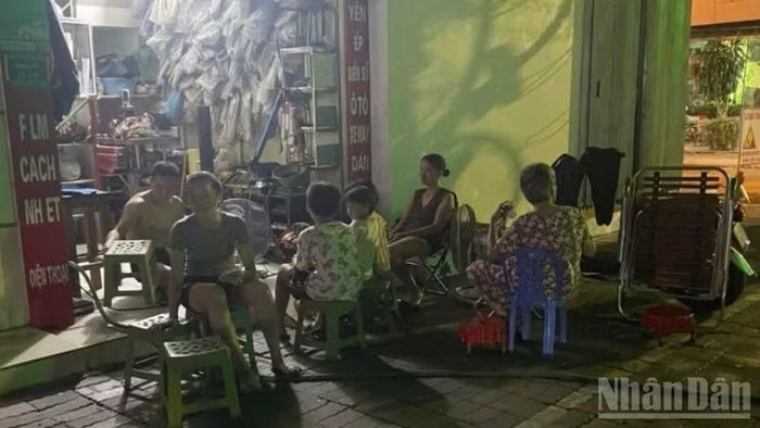 Người dân trên phố Hai Bà Trưng (phường Thái Bình, tỉnh Hưng Yên) dùng đèn ắc quy ngồi chờ trong lúc bị ngừng cấp điện.