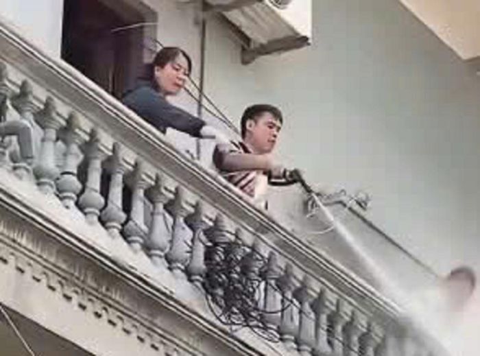 Người đàn ông liên tục dùng vòi nước xịt mạnh vào người thợ đang tháo dỡ công trình tại xã Tây Phương, TP Hà Nội. Ảnh: Cắt từ clip