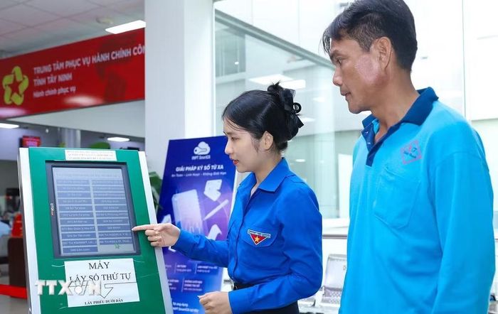 Thanh niên tình nguyện hướng dẫn người dân lấy số thứ tự tại Trung tâm phục vụ Hành chính công tỉnh Tây Ninh. (Ảnh: Thành Phương/TTXVN)