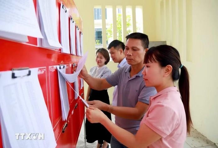 Người dân xã Tiên Tiến (Hưng Yên) xem danh sách cử tri và dự thảo Đề án sắp xếp lại thôn trên địa bàn. (Ảnh: Mạnh Khánh/TTXVN)