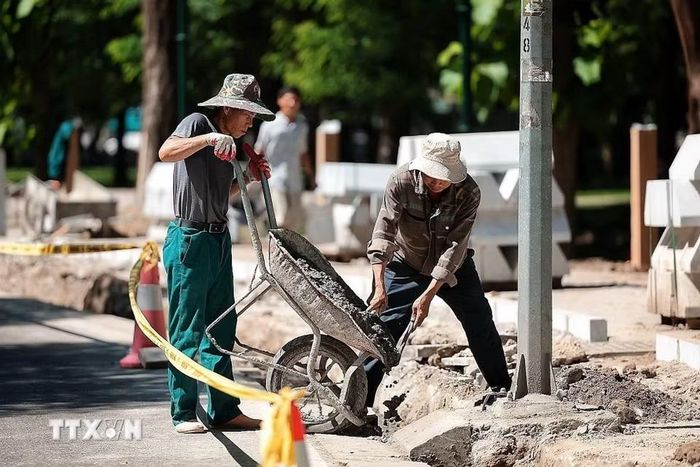 Công nhân xây dựng vẫn thi công trên vỉa hè dưới nắng nóng gay gắt. (Ảnh: Phạm Tuấn Anh/TTXVN)