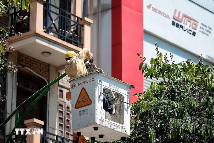 Công nhân Công ty TNHH Một thành viên Chiếu sáng và Thiết bị đô thị bảo dưỡng hệ thống chiếu sáng trên cao dưới nắng gắt trưa ngày 24/6. (Ảnh: Phạm Tuấn Anh/TTXVN)