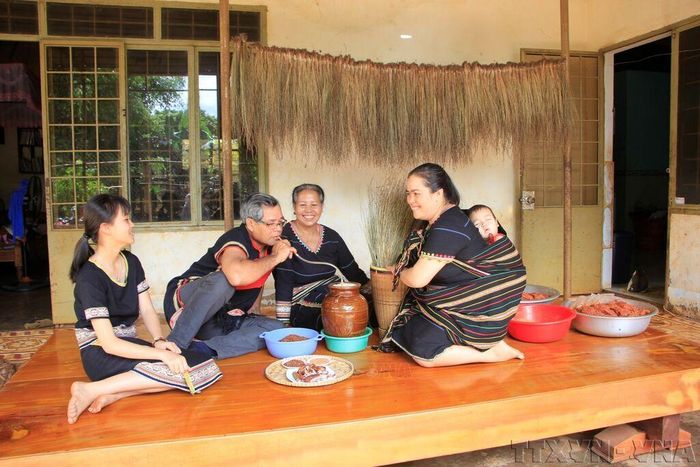 Một gia đình Tây Nguyên quây quần bên nhau thưởng thức các món ăn truyền thống và uống rượu cần. Ảnh tư liệu: Hồng Điệp/TTXVN