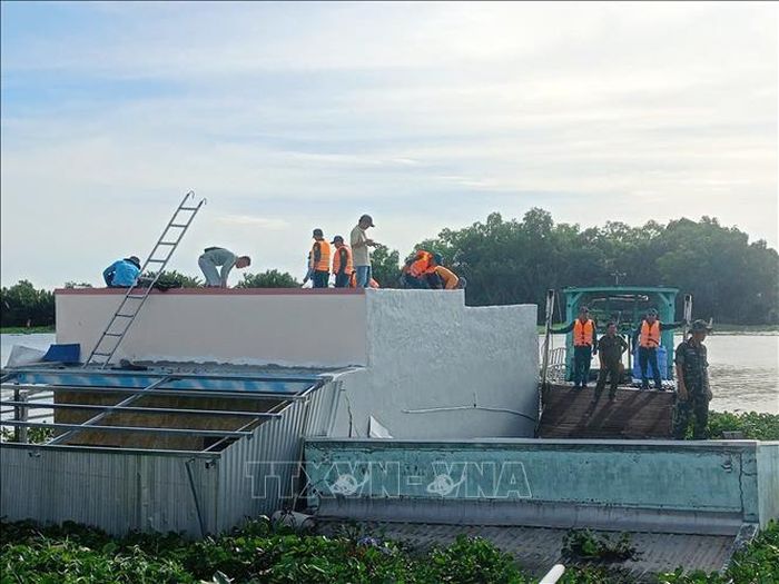 Lực lượng chức năng khoanh vùng khu vực nguy hiểm, hỗ trợ các hộ dân di dời tài sản và động viên hộ dân bị sạt lở nhà. Ảnh: TTXVN phát