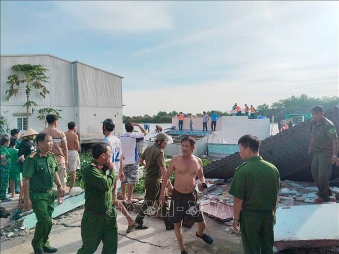 Lực lượng chức năng khoanh vùng khu vực nguy hiểm, hỗ trợ các hộ dân di dời tài sản và động viên hộ dân bị sạt lở nhà. Ảnh: TTXVN phát