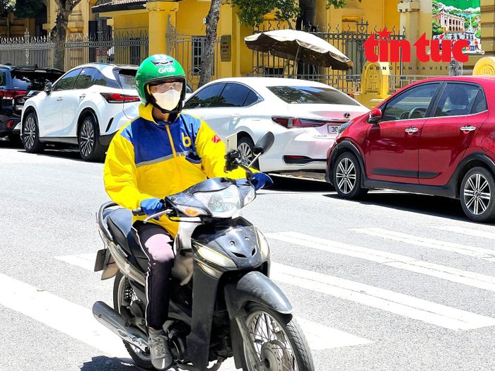 Lái xe ôm công nghệ trang bị nhiều lớp áo, bịt kín người để bảo vệ sức khỏe, duy trì công việc.