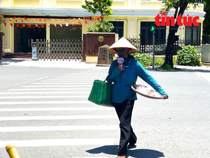Người bán hàng rong bịt kín mít, tay cầm thêm quạt mini, di chuyển qua từng con phố để kiếm thêm thu nhập.
