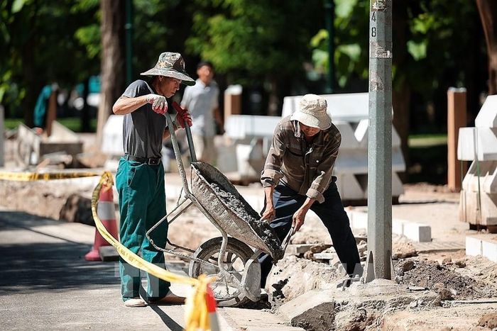 Công nhân xây dựng vẫn thi công trên vỉa hè dưới nắng nóng gay gắt. Ảnh: Phạm Tuấn Anh - TTXVN