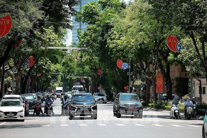 Người đi xe máy nép vào bóng râm khi chờ đèn đỏ giữa nắng nóng gay gắt tại Hà Nội. Ảnh: Phạm Tuấn Anh - TTXVN