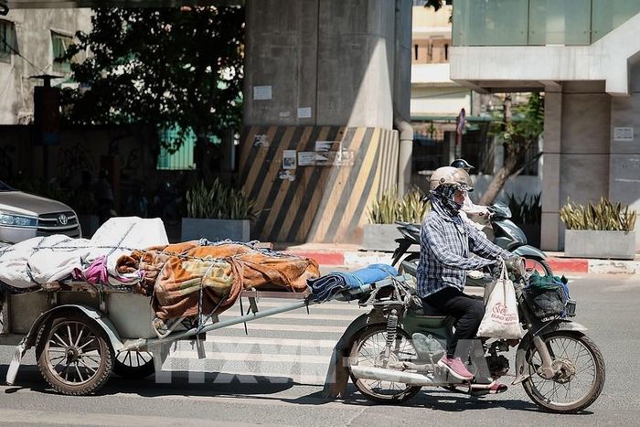 Người phụ nữ che kín mặt khi chở hàng trên phố trong nắng gắt để hạn chế tác động của ánh nắng trực tiếp. Ảnh: Phạm Tuấn Anh - TTXVN
