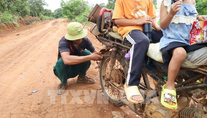 Để có thể lưu thông trong mùa mưa người dân phải lắp thêm xích chống trượt cho xe máy. Ảnh: Đậu Tất Thành - TTXVN