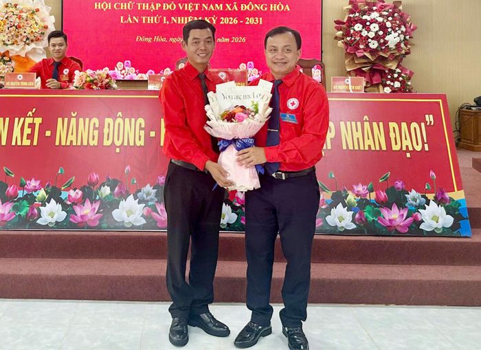 Phó Bí thư Thường trực Đảng ủy, Chủ tịch HĐND xã Đông Hòa Trương Minh Diệu (bìa phải) tặng hoa chúc mừng Chủ tịch Hội Chữ thập đỏ xã Đông Hòa Vũ Hải Dương.