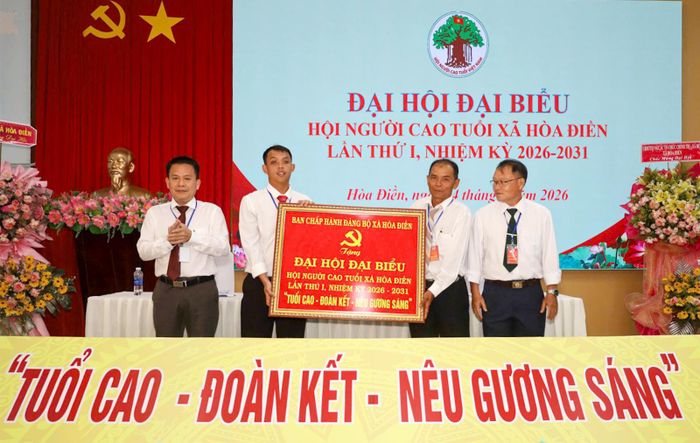 Bí thư Đảng ủy xã Lê Thanh Hưởng (bìa trái) tặng bức trướng chúc mừng đại hội