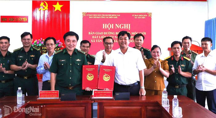 Đại tá Nguyễn Anh Đức và Phó Chủ tịch UBND xã Tân Tiến Nguyễn Đình Đoàn ký biên bản bàn giao hồ sơ hành chính về hệ thống đường biên giới, mốc giới cho xã Tân Tiến. Ảnh: Nguyệt Hà