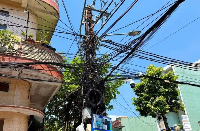  Cáp viễn thông chằng chịt như mạng nhện trên cột điện tại ngã tư Nguyễn Thái Học - Tô Hiến Thành. Ảnh: N.C 