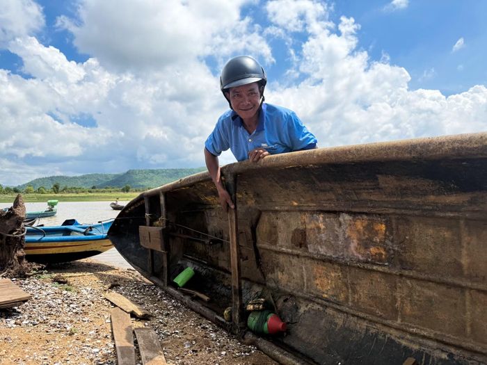  Anh Siu Song tranh thủ sửa chữa chiếc thuyền bị thủng do va phải gốc cây hóa lũa dưới lòng hồ. Ảnh: Hoàng Ngọc 