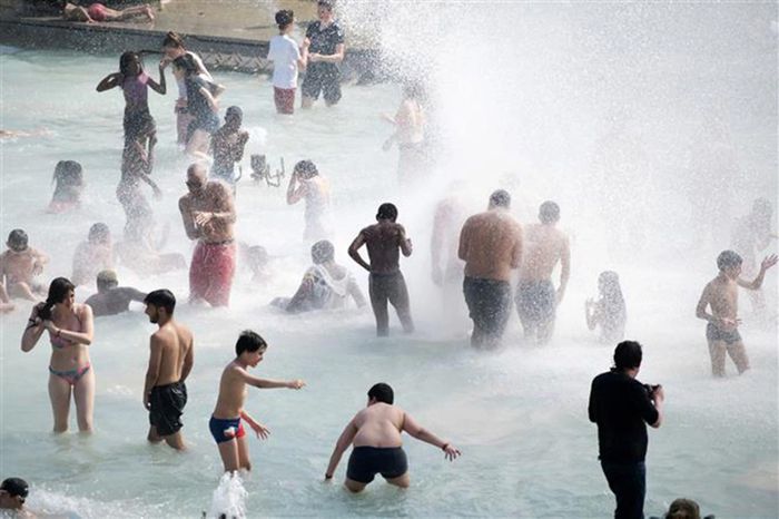 Người dân tránh nóng tại đài phun nước ở Paris, Pháp.