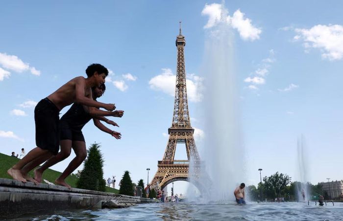Người dân giải nhiệt tại Đài phun nước Trocadero cạnh Tháp Eiffel ở Paris, Pháp, ngày 22/6. (Ảnh: Reuters)