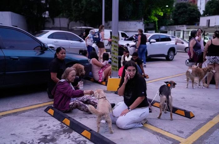 Người dân ngồi ngoài phố ở Caracas sau khi động đất xảy ra. Ảnh: Ariana Cubillos/ AP.