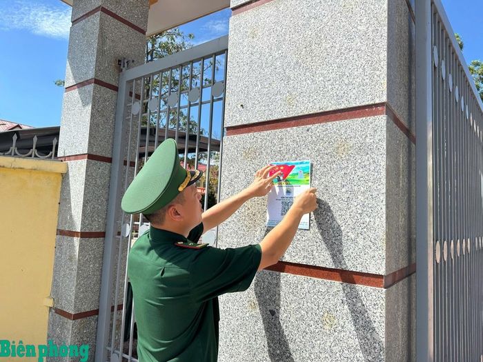 Cán bộ Đồn Biên phòng cửa khẩu Hoành Mô dán tờ hướng dẫn sử dụng mã QR “Hòm thư điện tử ẩn danh tiếp nhận tin báo, tố giác tội phạm”. Ảnh: Duy Khiêm