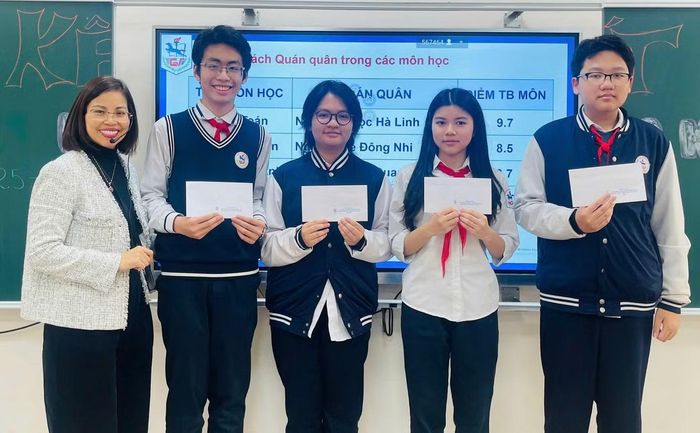 Khang (ngoài cùng bên phải) cùng các bạn được cô Loan (ngoài cùng bên trái) khen thưởng vì thành tích trong học tập.