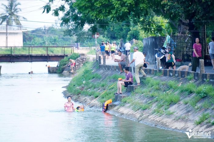 Người lớn buộc dây vào áo phao để cháu bé tắm khỏi bị trôi theo dòng nước. Ảnh: Lê Dương