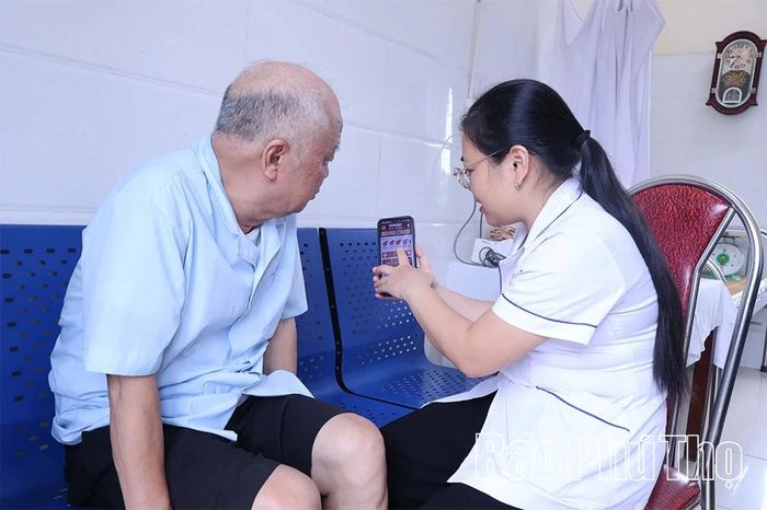 Người dân được nhân viên Trạm Y tế xã Phùng Nguyên hướng dẫn tích hợp Sổ sức khỏe điện tử trên VNeID.