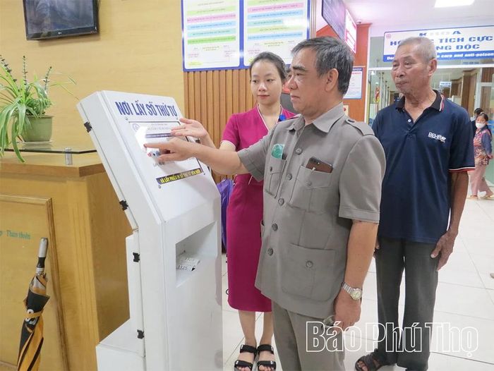 Nhân viên Trung tâm Y tế khu vực Lâm Thao hướng dẫn người dân lấy số thứ tự khám bệnh.