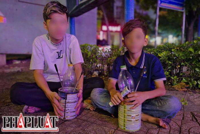  Trương Chí Dũng (16 tuổi, áo trắng) và Hồ Minh Tâm (12 tuổi) cùng nhau di chuyển trước các quán nhậu để thổi lửa mưu sinh. Ảnh: NHÓM PV 
