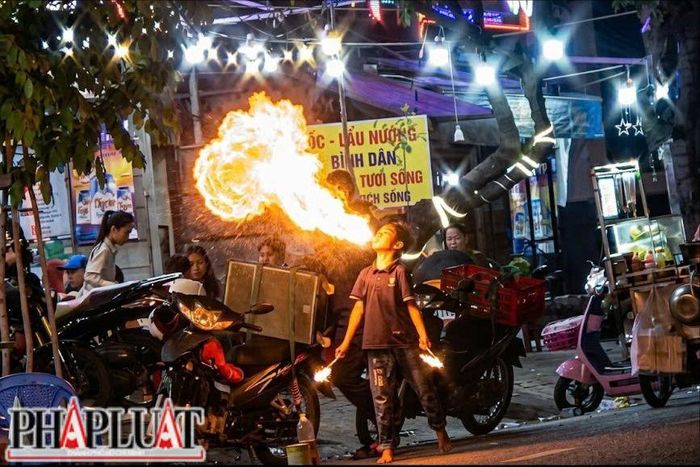  Hồ Minh Tâm, 12 tuổi, biểu diễn "xiếc lửa" tại các quán nhậu trên đường Phan Xích Long. Ảnh: NHÓM PV 