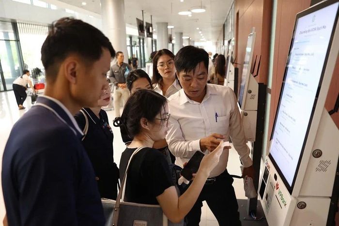 Cán bộ bệnh viên hướng dẫn người dân sử dụng máy lấy phiếu khám tự động. Ảnh: Tiến Long/TTXVN phát