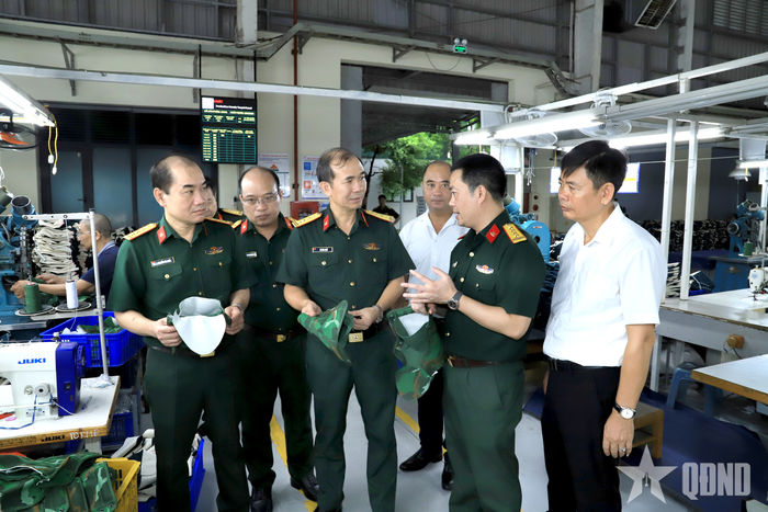 Các đại biểu thăm, nghe giới thiệu khu vực may mũ, giày vải cho chiến sĩ.