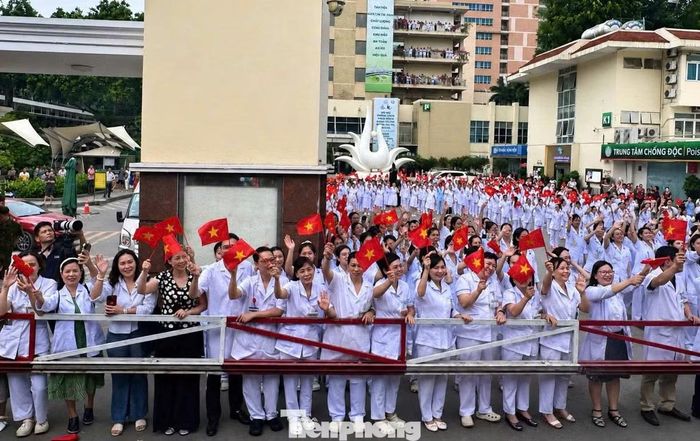 Bác sĩ và nhân viên y tế Bệnh viện Bạch Mai tại Hà Nội vẫy chào đồng nghiệp đi làm việc tại bệnh viện cơ sở 2 tại Ninh Bình trên tàu LP1 trong sáng nay. Ảnh: Lộc Liên.
