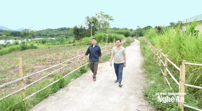Bí thư Chi bộ kiêm Trưởng bản Boong Kha Văn Nam (bên phải) đi trên con đường nội bản được mở từ nghĩa cử hiến đất, hiến cây của người dân. Ảnh: H.T