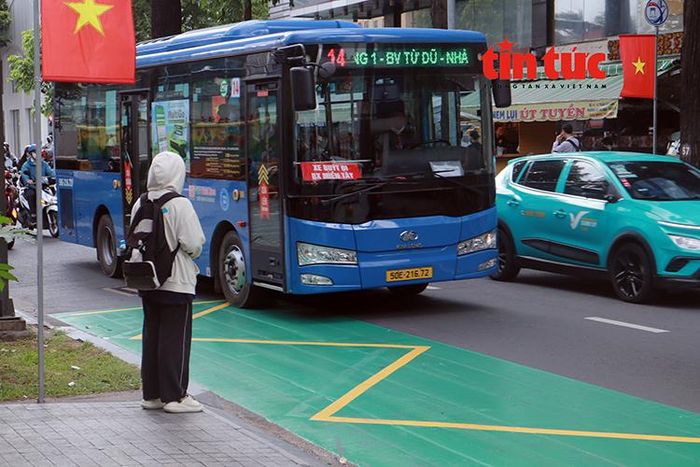 Hành khách đón xe buýt tại điểm dừng được sơn phản quang màu xanh trên đường Hai Bà Trưng.