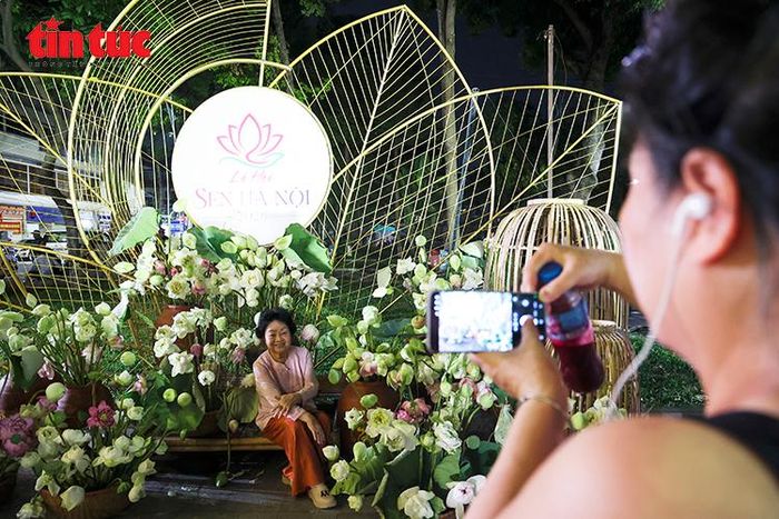 Người dân và du khách thích thú tham quan, lưu giữ khoảnh khắc bên không gian trưng bày sen tại Lễ hội Sen Hà Nội 2026 với chủ đề “Sắc Sen Hà Nội”.