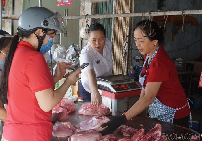 Cán bộ Trung tâm Dịch vụ tổng hợp xã Yên Bình trao đổi cùng các tiểu thương về công tác đảm bảo an toàn vệ sinh thực phẩm.