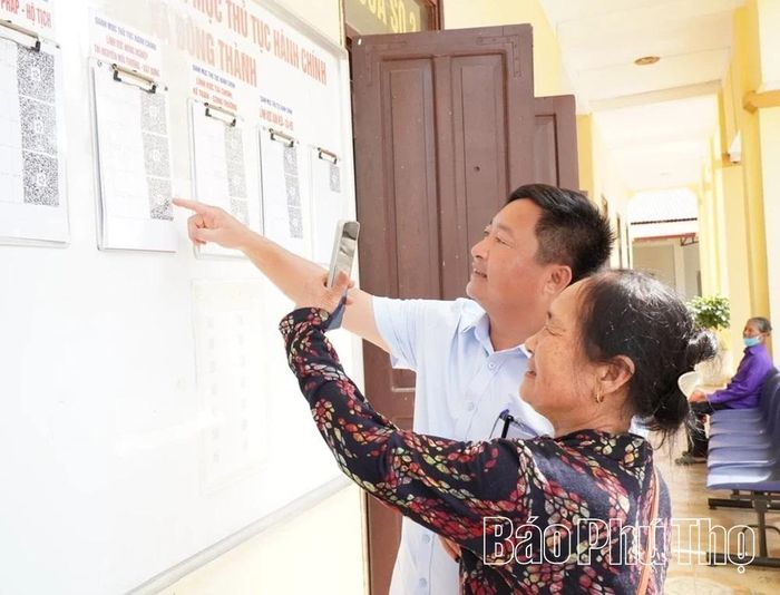 Cán bộ Trung tâm Phục vụ hành chính công xã Đông Thành hướng dẫn người dân sử dụng điện thoại thông minh đăng ký danh mục thủ tục hành chính.