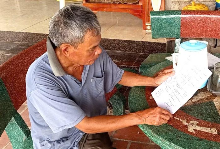 Ông Nguyễn Trọng Bảy xem lại giấy báo tử của anh trai liệt sĩ Nguyễn Trọng Cát.