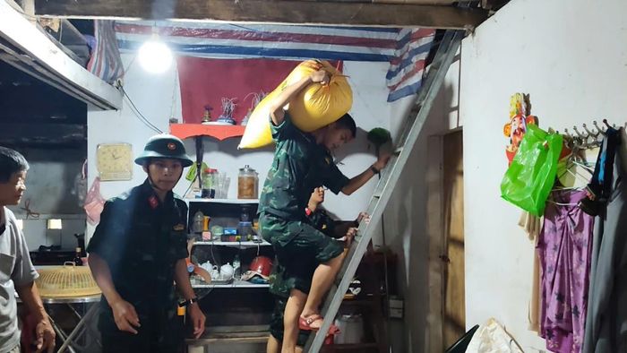 Cán bộ, chiến sĩ hỗ trợ người dân vận chuyển lương thực đến điểm an toàn.