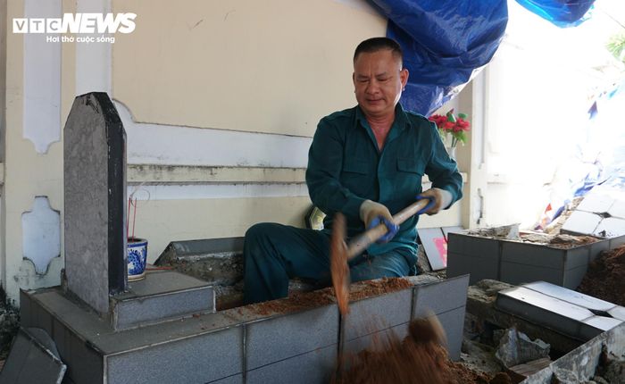 Anh Lê Văn Đình, dân quân phường Uông Bí, cẩn thận đào từng lớp đất tại một ngôi mộ liệt sĩ vô danh. (Ảnh: Tiến Thắng)
