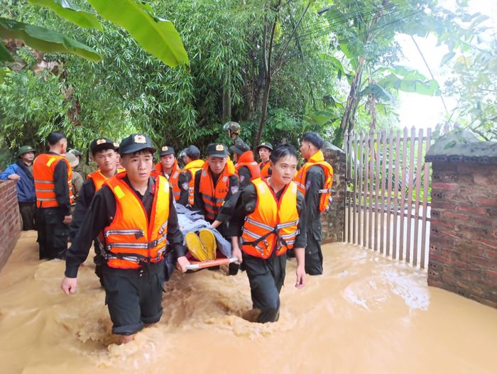  Cán bộ chiến sĩ công an hỗ trợ trường hợp cụ ông bị tai biến ra khỏi khu vực bị nước lũ chia cắt. (Ảnh: Công an Cao Bằng)