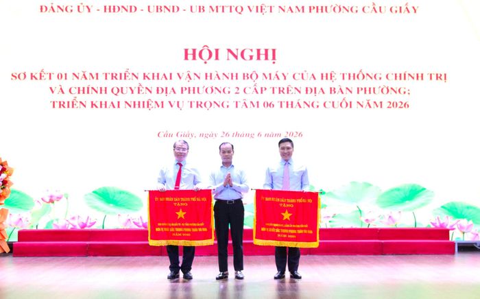 Đồng chí Nguyễn Hồng Nhật, Phó trưởng Ban Tổ chức Thành ủy Hà Nội trao Cờ thi đua của UBND thành phố Hà Nội cho 2 tập thể của phường Cầu Giấy. Ảnh: Vân Nhi