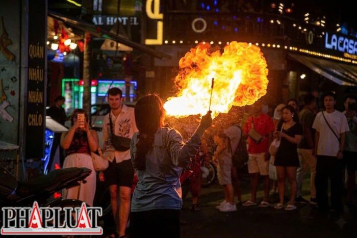  Một trẻ em ngậm dầu hỏa, phun lửa giữa dòng người qua lại tại khu vực trung tâm TP.HCM. Ảnh: NHÓM PV 