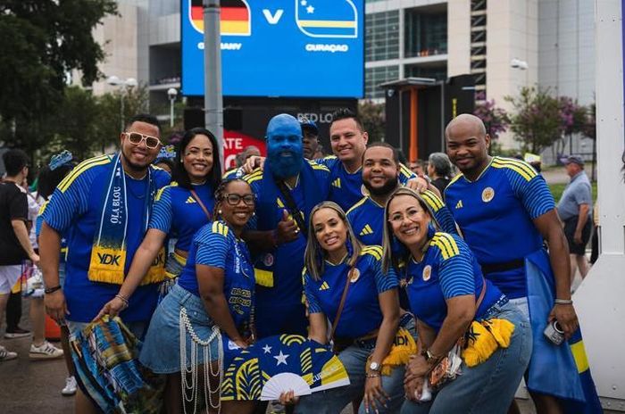  Payo và nhóm cổ động viên Curacao tập trung bên ngoài sân trước trận gặp Đức tại World Cup 2026 - kỳ World Cup đầu tiên trong lịch sử của quốc đảo nhỏ chỉ có khoảng 160.000 dân. Dù thua 1-7, Curacao vẫn ghi được bàn thắng đầu tiên tại World Cup ngay trước một đội bóng lớn như Đức. Với Payo, đó vẫn là một khoảnh khắc lịch sử đáng tự hào. 