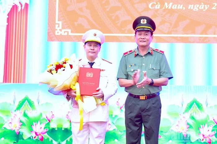 Thừa ủy quyền, Thiếu tướng Hồ Việt Triều, Giám đốc Công an tỉnh Cà Mau (bên phải), trao Quyết định của Bộ trưởng Công an và tặng hoa chúc mừng Đại tá Lê Mạnh Hùng.