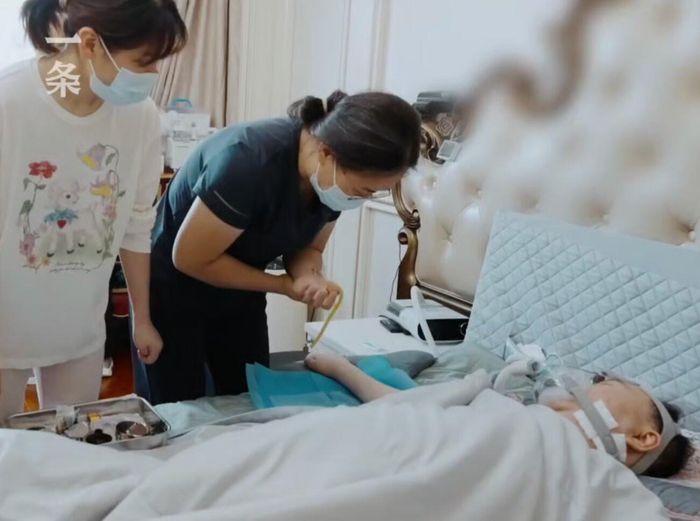 Cai Lei nằm trên giường được một y tá chăm sóc. Ảnh: Yitiao