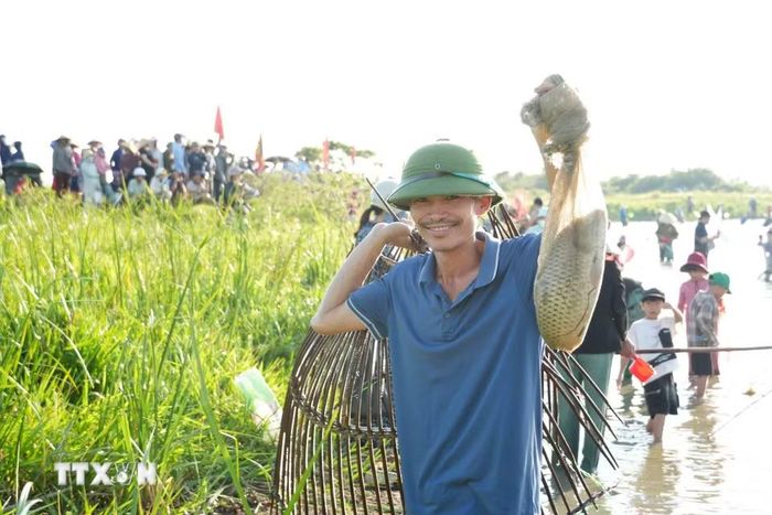 Người dân phấn khởi khoe thành quả sau khi tham gia đánh bắt cá bằng ngư cụ truyền thống tại lễ hội. (Ảnh: Hữu Quyết/TTXVN)