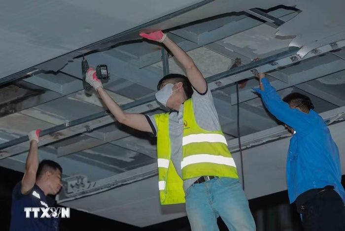 Các công nhân khẩn trương, cẩn thận tháo dỡ những tấm ốp Alu bị vỡ tại khu vực nhà ga Láng trong đêm. (Ảnh: Phan Phương/TTXVN)